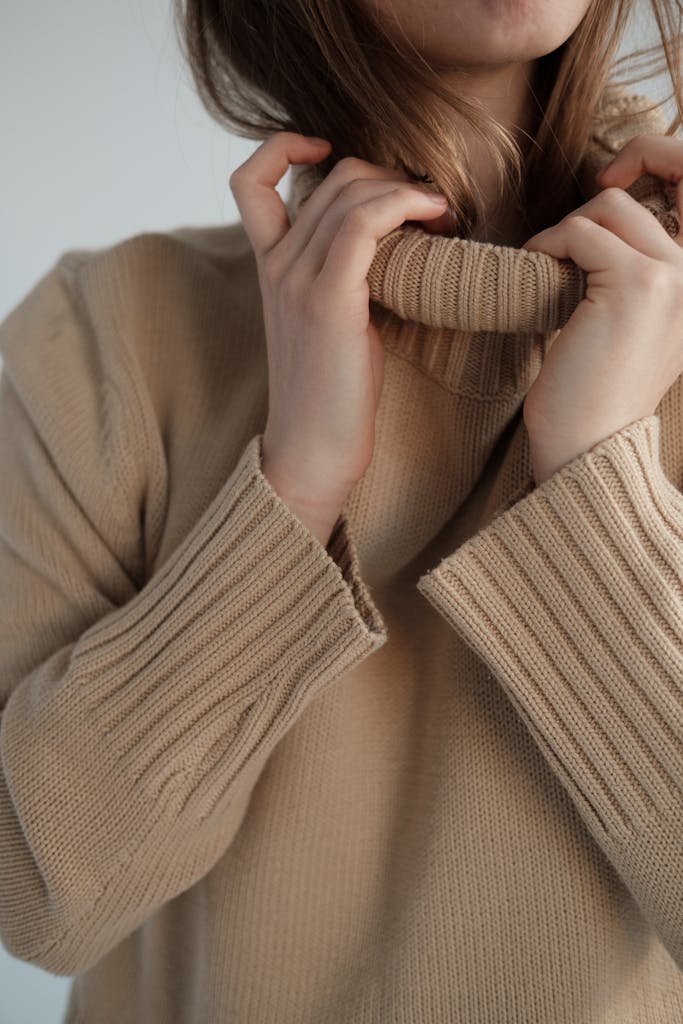 Crop unrecognizable female with long hair wearing soft warm sweater with long collar
