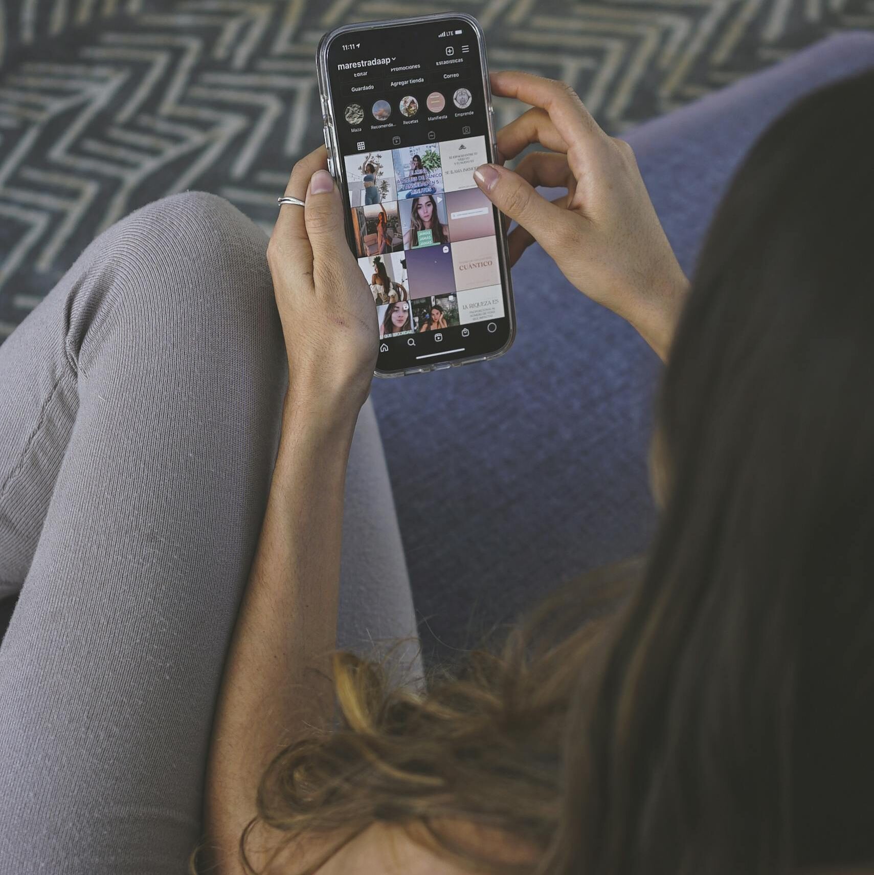 An adult woman browsing social media on a smartphone indoors.