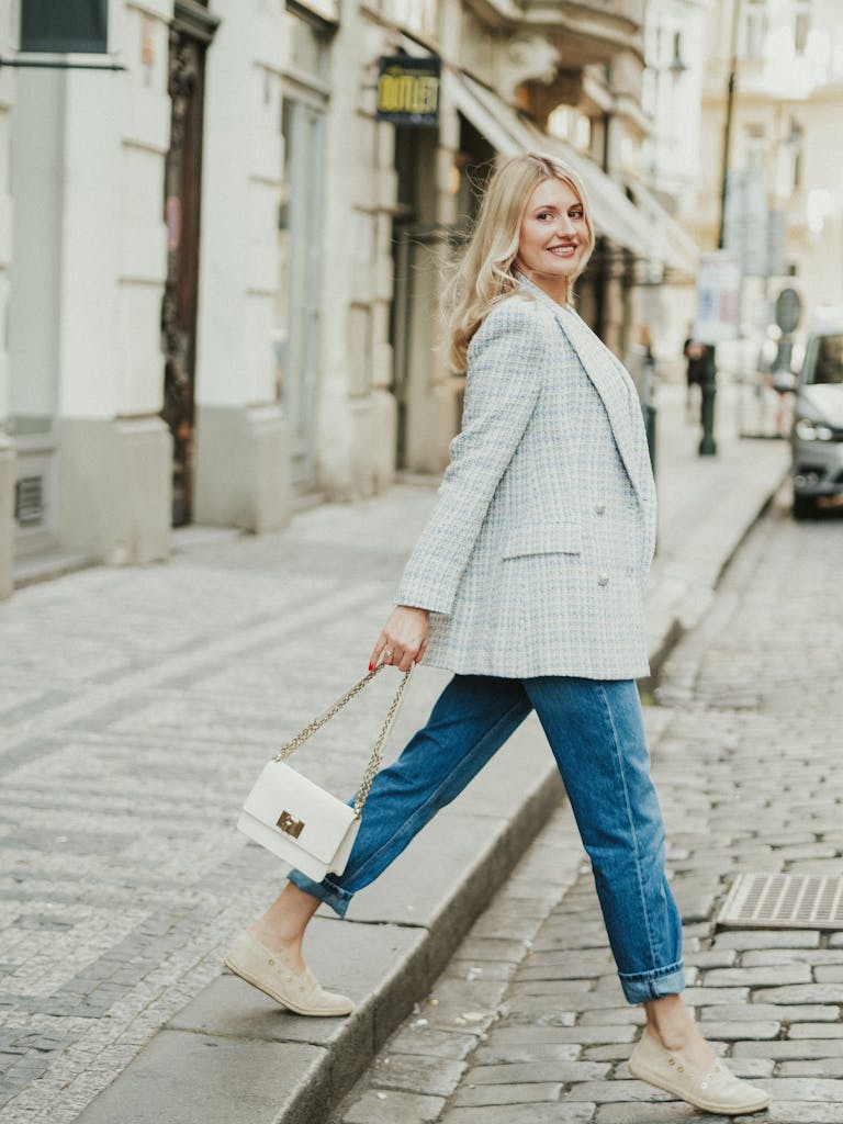 Elegant woman in business casual attire walking in a scenic European old town street.