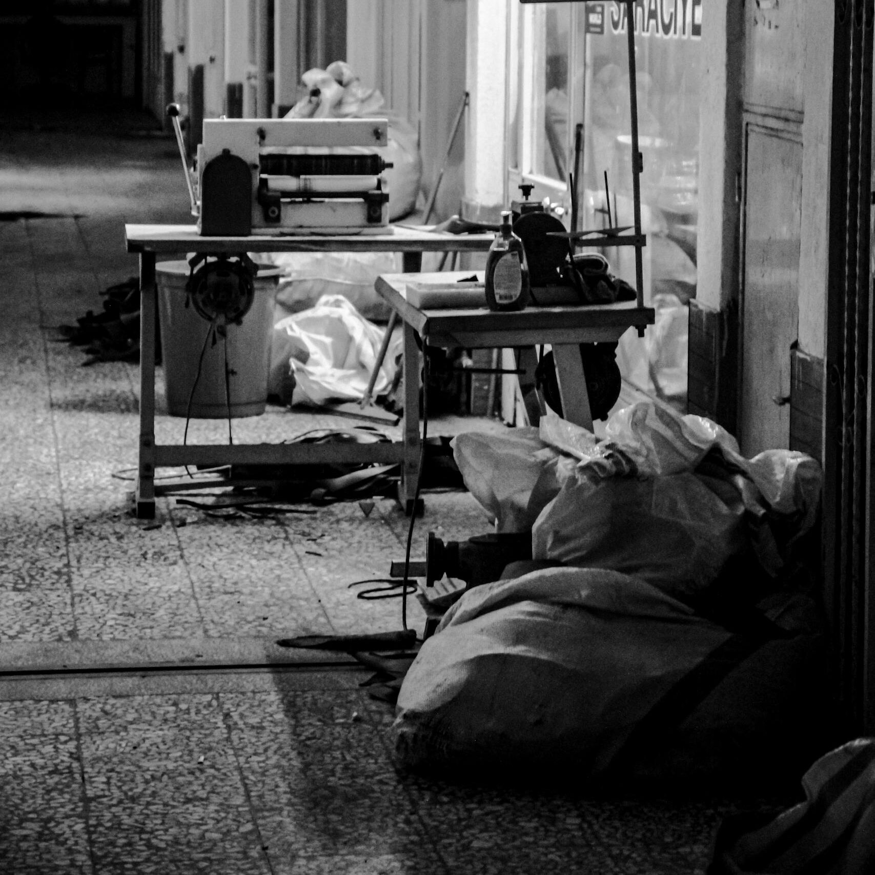 Monochrome image of an indoor sewing workshop with machines and fabric.
