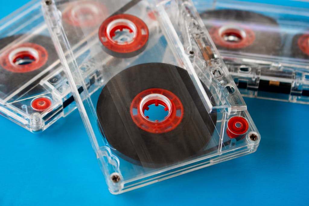 Close-up of vintage transparent audio cassettes with red reels on a bright blue background.