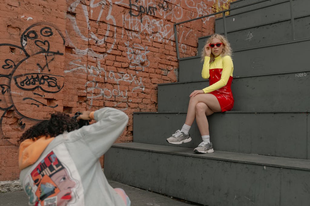 Stylish woman poses on urban steps, capturing street fashion amidst graffiti.