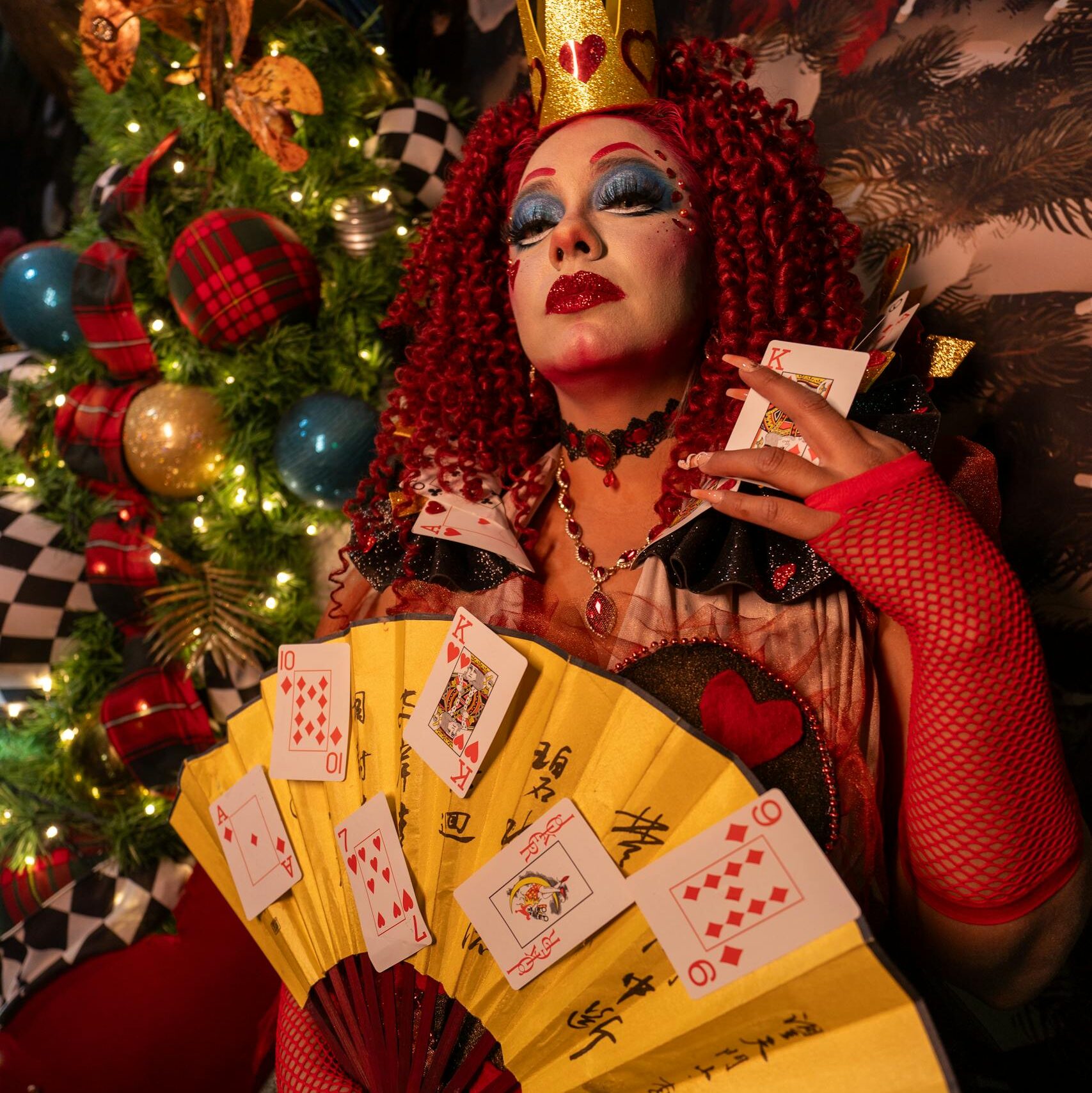 Queen character in vibrant costume, art makeup, and playing cards, evoking fantasy vibes.